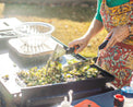 Woman cooking on the griddle with two spatulas. 